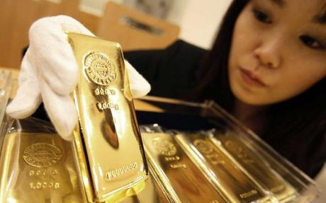 woman with gold bar - Citigroup says gold could rise above $2,000 next year as world unravels